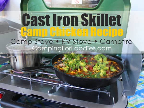 Chicken recipe cast iron skillet by CampingForFoodies features a large cast iron skillet sitting on a propane camp stove. The pot is filled with a dinner that is ready to be served. The chicken is cooked with black beans and corn and is topped with fresh avocado and cilantro with text over the image that reads cast iron skillet camp chicken recipe, camp stove, RV stove, and campfire.