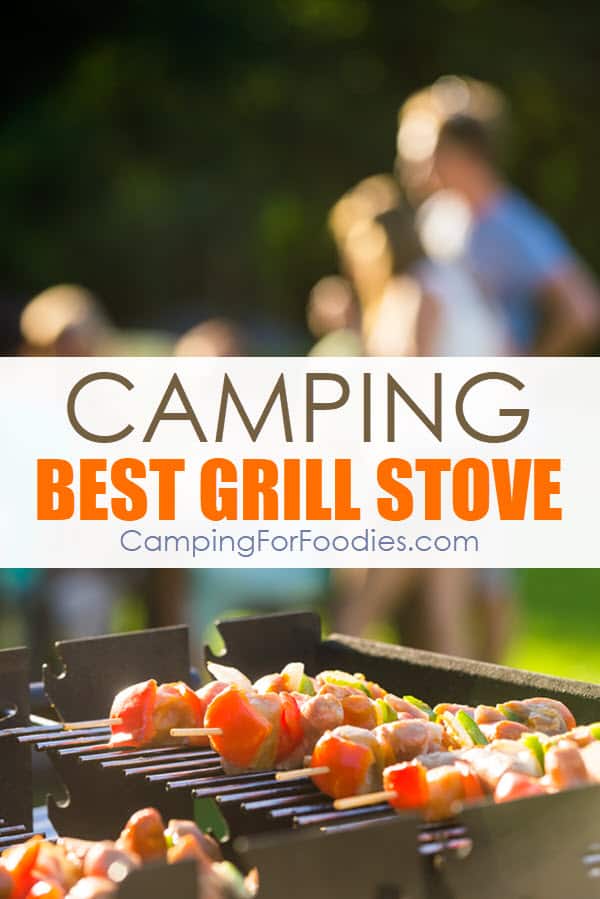 This is an image of shish kabob sticks cooking on a grill outside on a bright sunny day with campers in the background standing around and sitting at a picnic table in the woods with bright green grass. The text over the image refers to the gear review of the Best Camping Grill Stove Outdoor Camp Kitchen Cooking Gear by CampingForFoodies