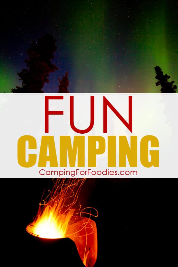 Camping Fun Includes Ideas For Activities And Safety Tips To Keep Trips Enjoyable by CampingForFoodies is an image of a bright glowing campfire with the silhouettes of trees in the background under the blue, yellow and green streaks in the Northern Lights evening sky filled with stars and text over the image reads fun camping.