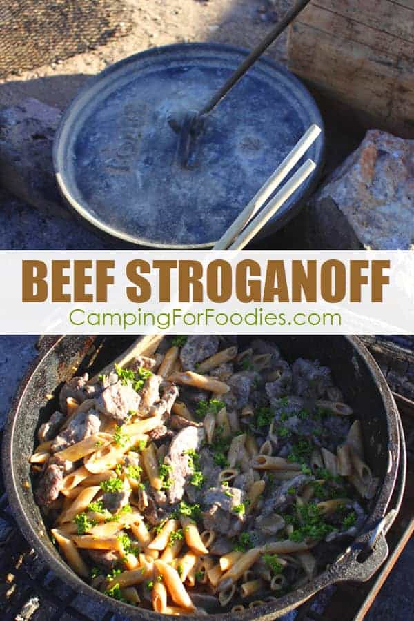 This Dutch Oven Beef Stroganoff Camping Recipe by CampingForFoodies is ready for serving as it sits in a camp Dutch oven inside a campfire ring on a sunny camp day. The golden colored pasta is mixed with the creamy sauce and meat, all covered with bright green fresh parsley.