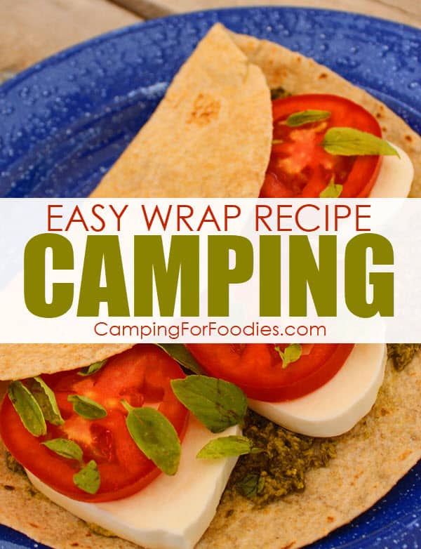 Pesto Tomato Wraps Easy Camping Recipe by CampingForFoodies is an image of a no-cook, vegetarian camping recipe on a wheat tortilla and stacked with basil pesto, fresh red roma tomatoes, creamy white fresh mozzarella cheese and basil leaves sitting on a blue camping plate ready for serving at the campsite.