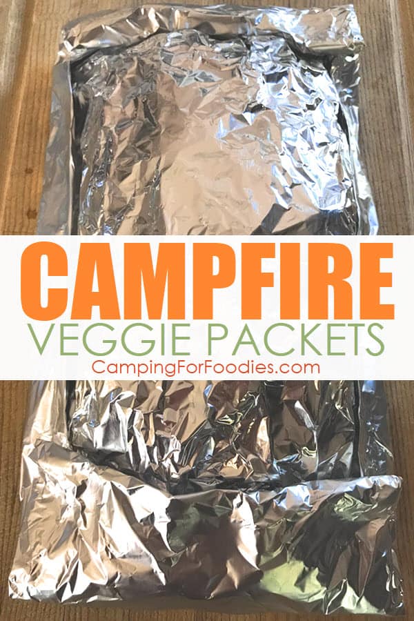 Campfire Veggie Packets by CampingForFoodies features an aluminum foil folded packet that is stuffed and ready to be cooked over campfire coals or a camping grill powered by charcoal briquettes or propane and text over the image that reads campfire veggie packets.