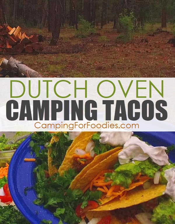 Brown Dutch Oven Camping Tacos by CampingForFoodies features a blue camping plate filled with ground beef hamburger tacos in hard shells topped with shredded cheddar cheese, cilantro, onions, tomatoes, guacamole and sour cream with a background of a forest with green trees and a campfire wood pile and text over the image that reads Dutch oven camping tacos.