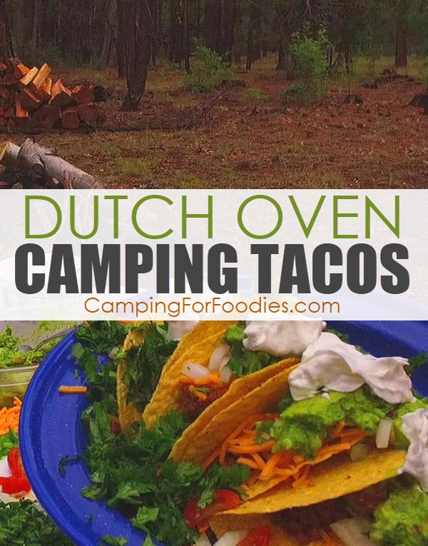 Dutch Oven Camping Tacos by CampingForFoodies features a blue camping plate filled with ground beef hamburger tacos in hard shells topped with shredded cheddar cheese, cilantro, onions, tomatoes, guacamole and sour cream with a background of a forest with green trees and a campfire wood pile and text over the image that reads Dutch oven camping tacos.