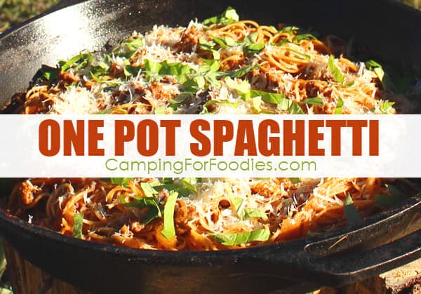 Camp Cooking Tip One Pot Spaghetti Camping Recipe by CampingForFoodies features a big cast iron skillet filled with pasta cooked in a sausage tomato sauce and topped with fresh basil and parmesan cheese with text over the image that reads one pot spaghetti.