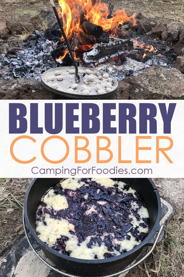 Easy Cast Iron Dutch Oven Blueberry Cobbler by CampingForFoodies features a camp cooking scene with a campfire blazing in the background and sitting on the ground in front of the campfire ring is a blueberry cobbler that is baked and ready to serve from a cast iron Dutch oven with text over the image that reads blueberry cobbler.