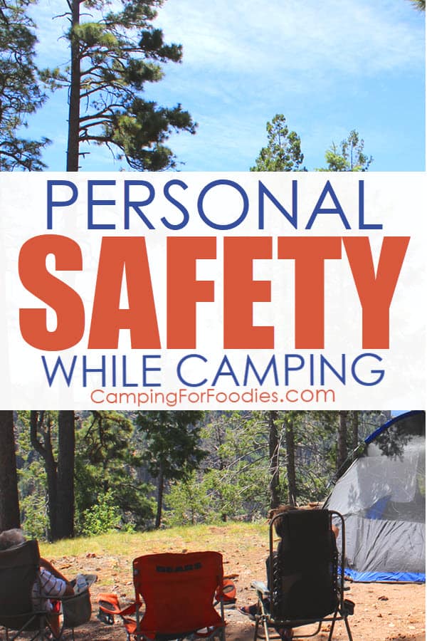 Personal Safety While Camping by CampingForFoodies features a camp scene in a remote wooded area in the mountains with three camp chairs set up and two people relaxing in them next to a tent under a bright blue sky with text over the image that reads personal safety while camping.