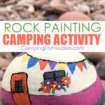 Rock Painting Camping Activity by CampingForFoodies features a brightly colored painted rock craft project that looks like a little cream and pink retro camper decorated with blue, orange, purple and yellow flags and orange and purple flowers in a window box under the trailer’s window the orange door welcomes visitors and round river rocks are piled in the background with text over the image that reads rock painting camping activity.