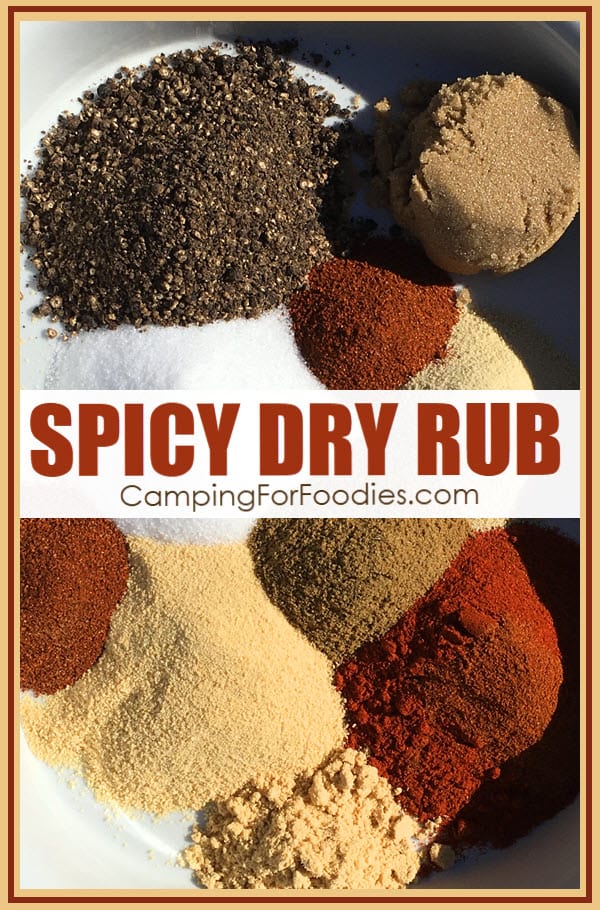 Spicy Hot Dry Rub by CampingForFoodies features a mixing bowl filled with piles of spices that are ready to be mixed to create a dry rub for cooking including brown sugar, paprika, garlic powder, salt, black pepper, onion powder, cumin, cayenne pepper, dry mustard and chili powder with text over the image that reads spicy dry rub.