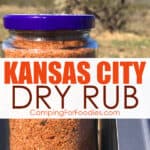 Kansas City Dry Rub by CampingForFoodies features a glass jar filled with a red and brown colored mix of spices making a dry rub for smoking meats that is sitting on the top of a pellet box on a portable smoker with mountains and desert plants in the background at a campsite with text over the image that reads Kansas City Dry Rub.