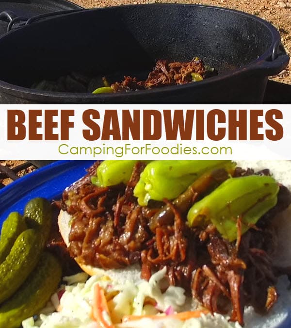 Dutch Oven Beef Sandwiches by CampingForFoodies features a shredded beef sandwich on a hoagie roll topped with mildly spicy green peppers on a blue camping plate alongside a serving of coleslaw and dill pickles ready to be served and setting in front of a black cast iron camp Dutch oven with text over the image that reads Beef Sandwiches.