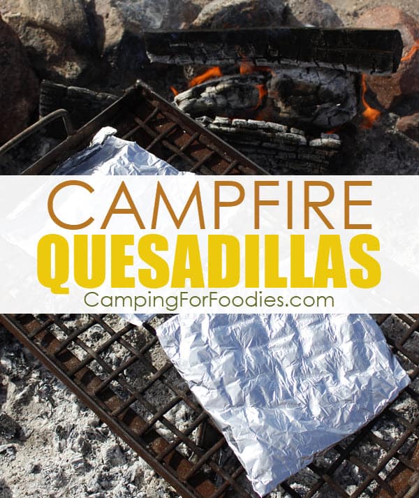 Campfire Foil Packet Quesadillas Recipe by CampingForFoodies features two foil packets folded into large squares that are set on top of a campfire cooking grate over coals in a camp fire ring with burning logs in the background with text over the image that reads campfire quesadillas.