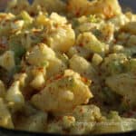Polish Potato Salad Recipe by CampingForFoodies features a bowl of fresh potato salad tossed in a light yellow colored dressing made from mustard and mayonnaise along with freshly chopped onion, celery and hard boiled eggs then sprinkled with deep red paprika.