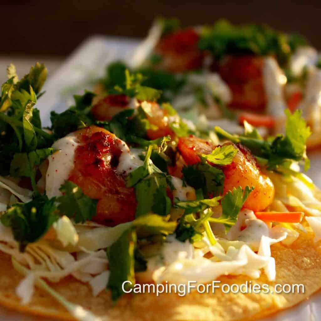 Chili Lime Shrimp Tacos by CampingForFoodies features a corn tortilla topped with chili lime marinated shrimp that's grilled to golden brown color, served with slaw and drizzled with jalapeno lime sauce.