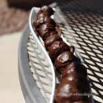Chocolate Covered Peanut Butter Balls by CampingForFoodies features a row of chocolate covered, ball-shaped cookies sitting in a serving tray on a table.